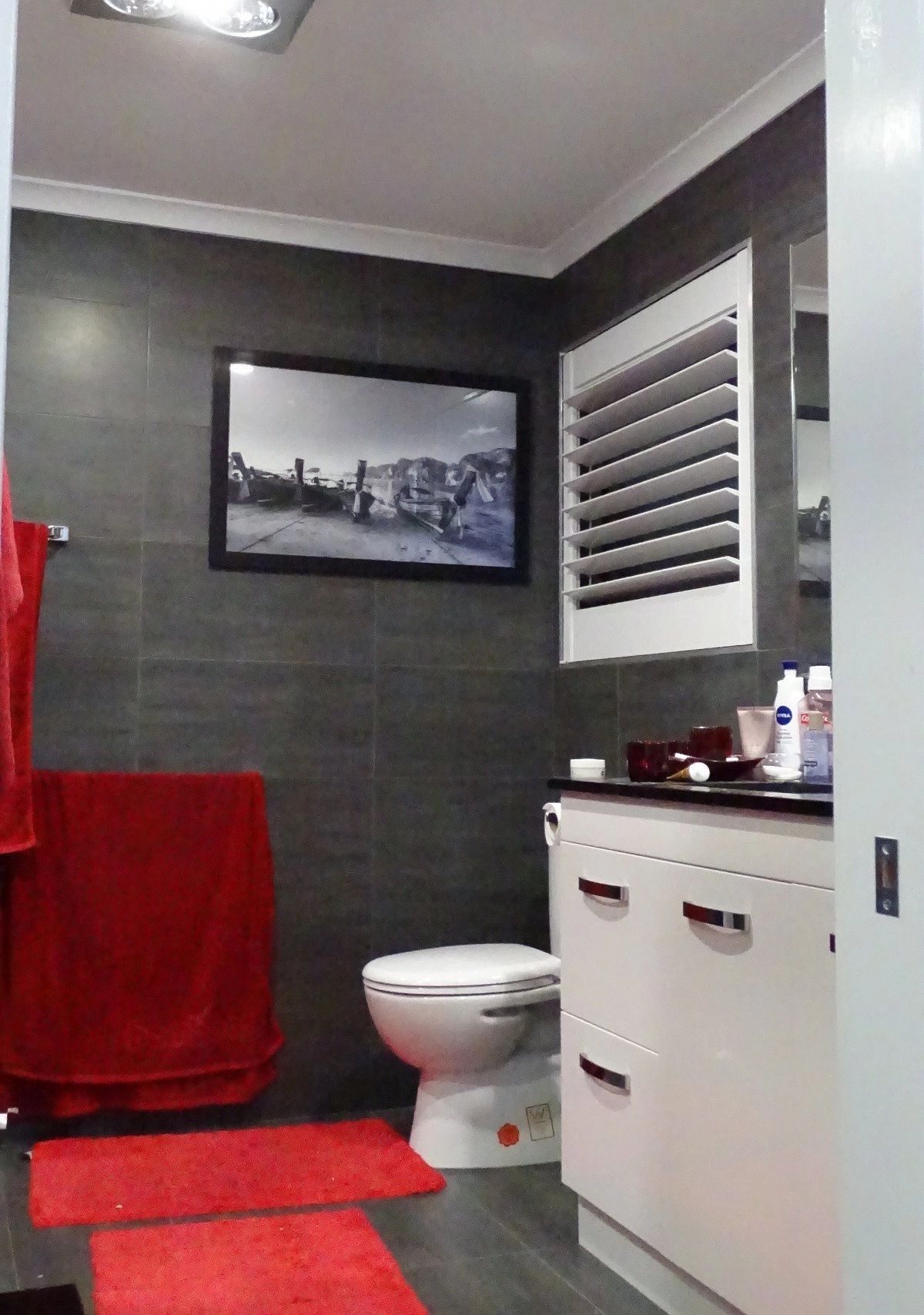 Contemporary bathroom featuring a red towel, rug, and a framed black and white photograph on the wall.