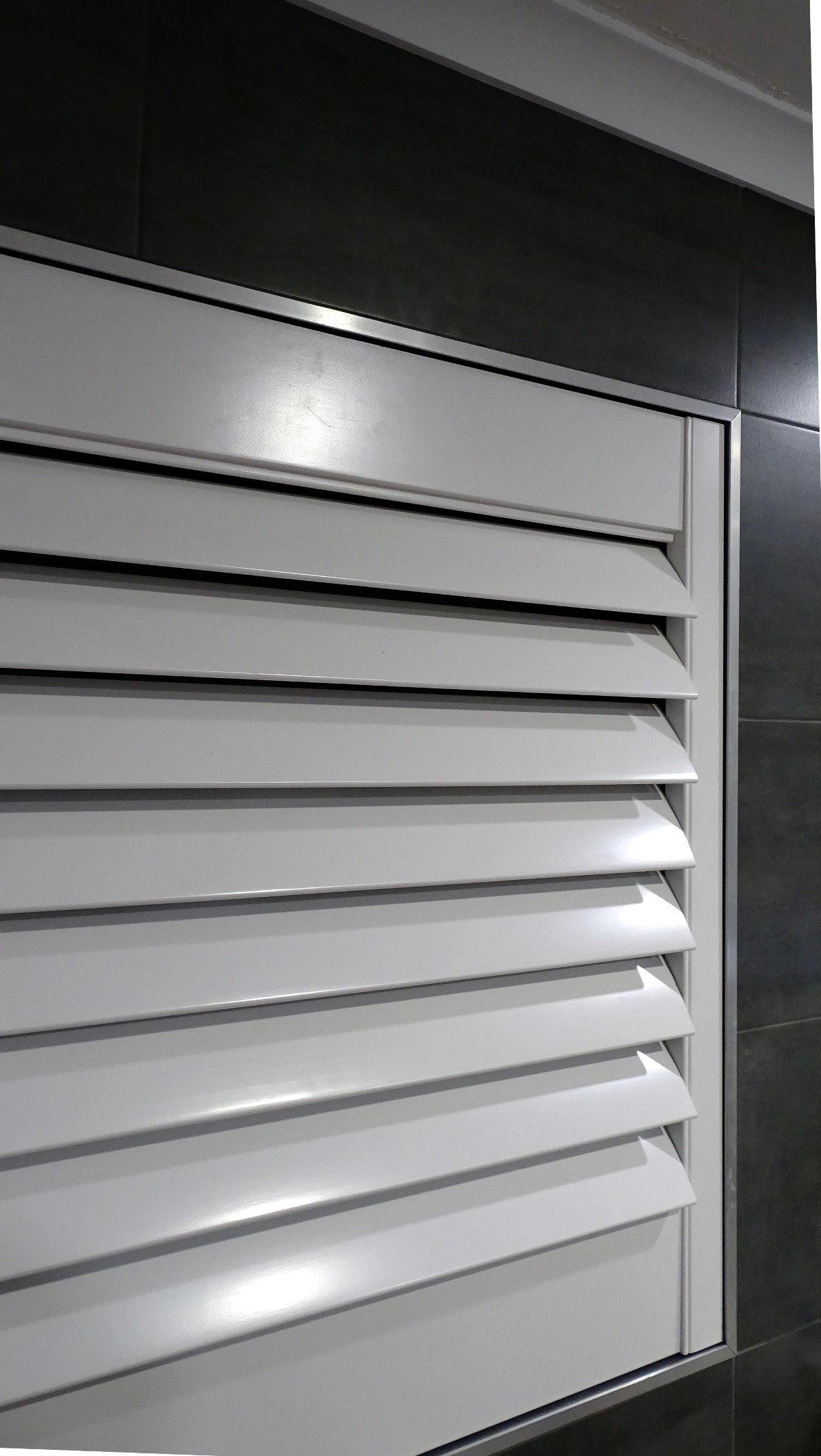White plantation shutter with horizontal slats installed on a wall, providing light control.