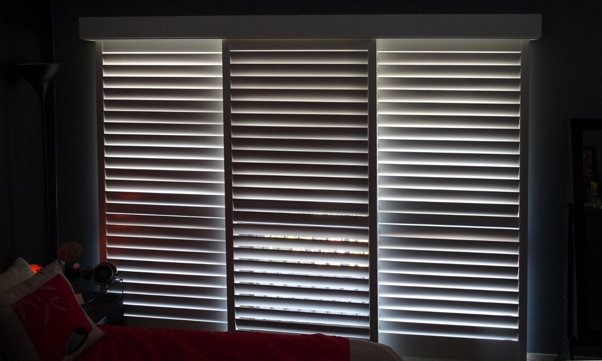 Plantation shutters with horizontal slats allowing light to filter through in a room setting.