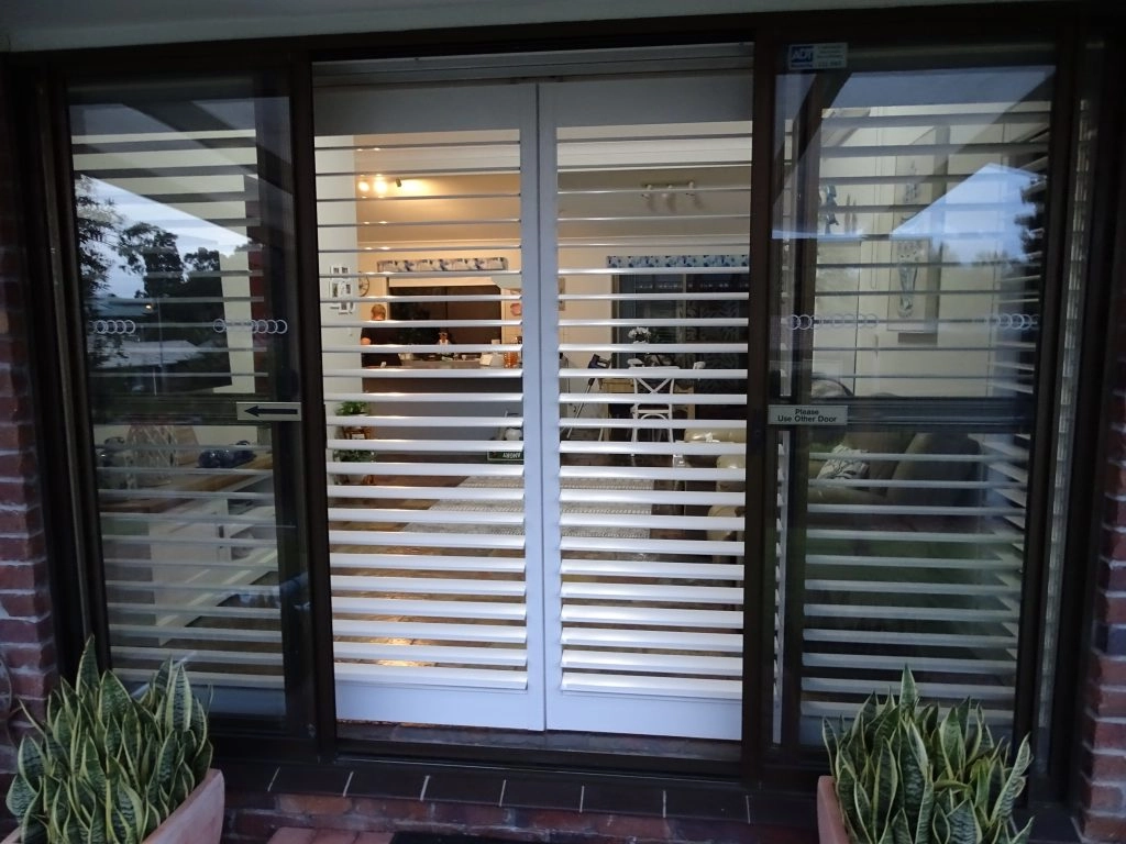 a glass sliding door furnished with plantation shutter blinds