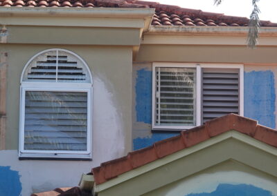 View from road of arched window with shutter blind in it